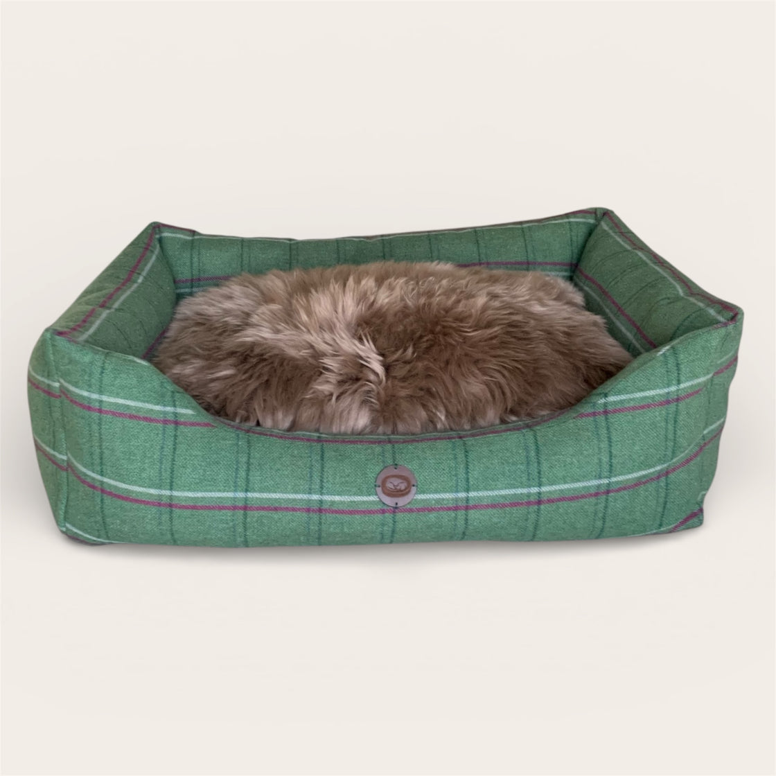 Green tweed wool filled pet bed with a sheepskin topper on a white background